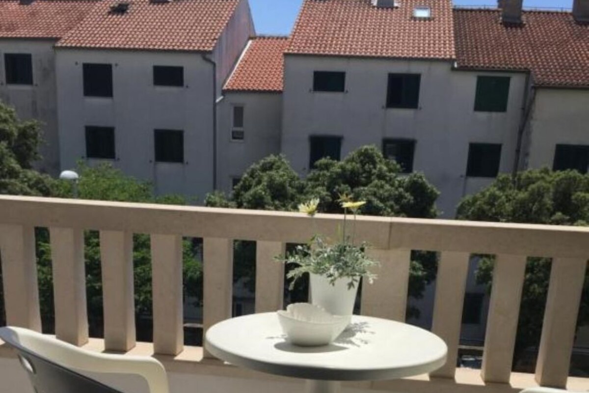 A balcony with two chairs and a table, a potted plant, and a railing.