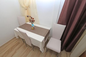 A small dining table with a vase of dried flowers, two chairs, a brown table runner, and a curtain. - Apartments and Room Tattoo (Makarska)