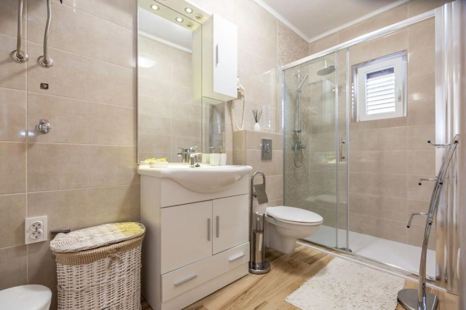 A bathroom with a shower, toilet, sink, and a wicker basket.