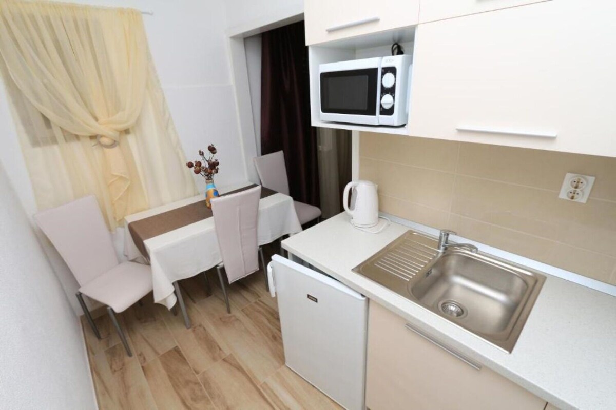 A compact kitchenette with a microwave, sink, and small refrigerator.
