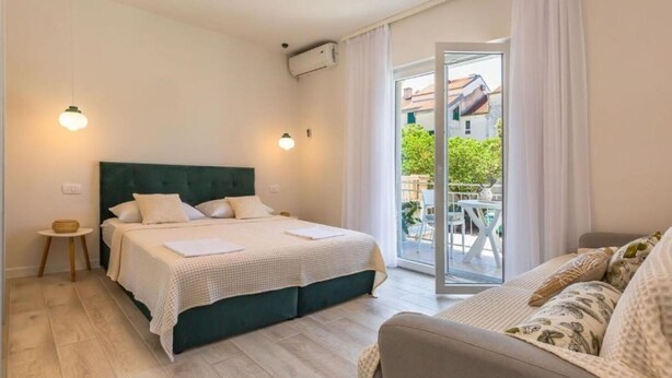 Une chambre à coucher comprenant un lit, une petite table, un canapé et une porte-fenêtre coulissante donnant sur un espace extérieur.