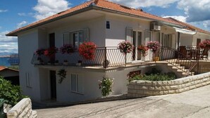 Ein zweistöckiges Haus mit Balkon, Treppe und Meerblick.