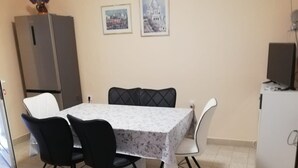 Ein Essbereich mit Tisch, Stühlen, einem Kühlschrank und einem kleinen Fernseher.