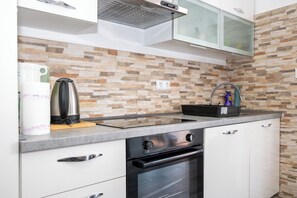Eine moderne Küche mit Steinrückwand, Backofen und Dunstabzugshaube aus Edelstahl.