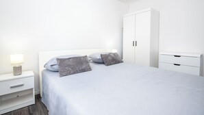 A bedroom with a bed, nightstand, lamp, and wardrobe. - Apartment Sunset (Podstrana)