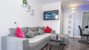 A modern living room with a grey sofa, a coffee table, and a TV mounted on the wall. - Apartment Sunset (Podstrana)