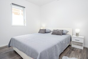 Ein Schlafzimmer mit Bett, Kissen, Nachttisch und Fenster.
