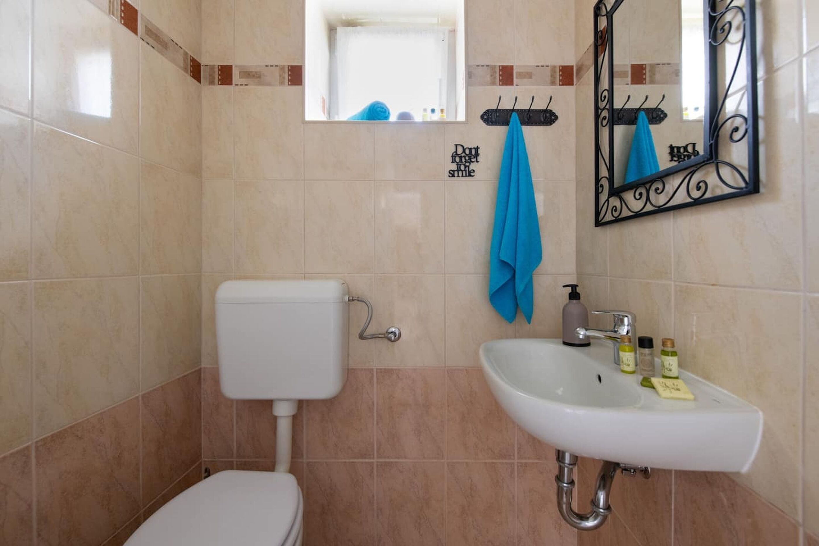 A bathroom with a toilet, sink, mirror, and a towel rack.