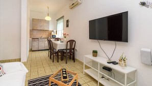 A compact living space with a dining area, kitchenette, and a mounted TV. - Apartment Tatjana (Rab)