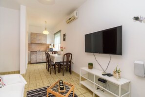 Ein kompakter Wohnbereich mit Essplatz, Küchenzeile und einem an der Wand befestigten Fernseher.