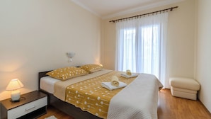 A bedroom with a bed, nightstand, lamp, and a chair. - Apartment Tatjana (Rab)
