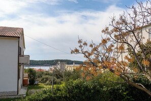 Ein Wohngebiet mit einem weißen Gebäude, einem Baum mit Herbstlaub und einer entfernten Wasseransicht.