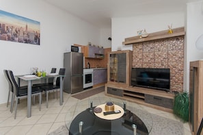 Ein modernes Wohnzimmer mit Essbereich, Küche und einem Kamin aus Stein.