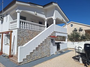 A two-story house with a stone facade, a covered porch, and a boat in the driveway. - Apartments Apartmani Didovi Dvori (Razanac)
