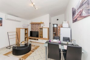 A modern living room with a TV, seating, and a dining area. - Apartments Apartmani Didovi Dvori (Razanac)