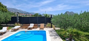 A swimming pool with lounge chairs, a wooden deck, and a view of mountains. - House Villa Olives Garden (Solin)