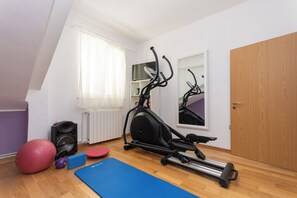 Ein Zimmer mit Deckenventilator, Laufband, rotem Übungsball, blauer Matte und Lautsprecher.