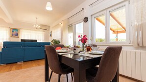 A modern kitchen with a dining table, chairs, and a blue sofa. - Apartment Neda With Jacuzzi (Bilice)