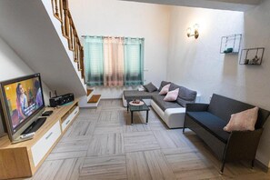 Ein Wohnzimmer mit Fernseher, Sofa und Treppe.