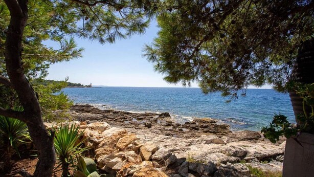 A rocky shoreline with a clear view of the sea and a distant lighthouse. - House Ivana (Milna)