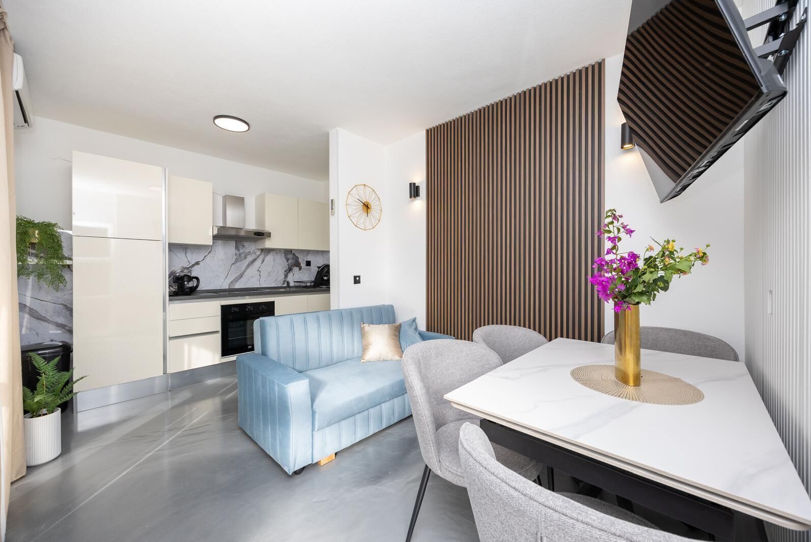A modern kitchen with white cabinets, a marble backsplash, and a built-in oven.