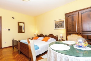 A bedroom with a bed, bedside table, lamp, and a dining table with a glass top.