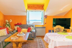 A living room with a sofa, a table, a window with a view, and a television. - Apartments Sunset Near Beach (Podstrana)