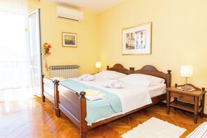 Un dormitorio con cama de madera, mesitas de noche con lámparas, un radiador y dos cuadros en la pared.