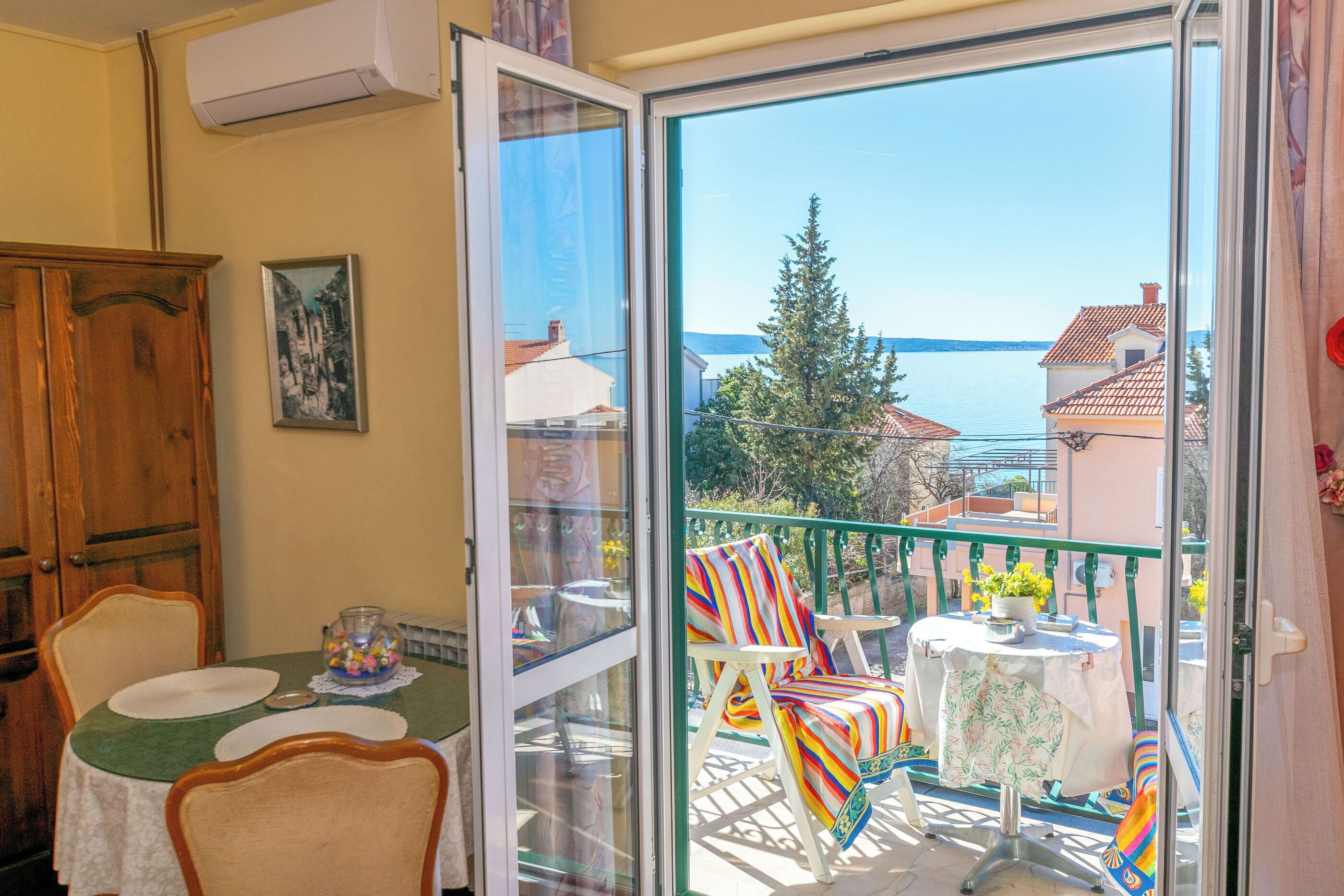 A balcony with a table, chairs, and a view of the sea.