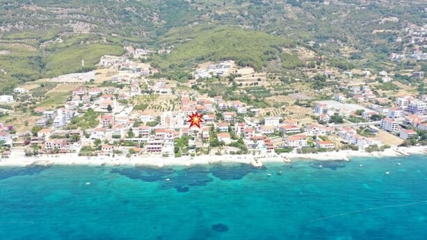 Vista aérea de un pueblo costero con edificios a lo largo de la orilla y una vista despejada del mar.