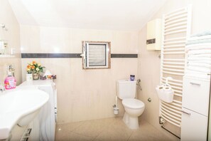 A bathroom with a toilet, sink, and towel rack. - Apartments Sunset Near Beach (Podstrana)