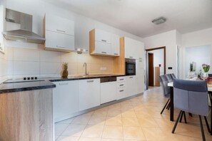 Eine moderne Küche mit weißen Schränken, einer Granit-Arbeitsplatte und einem Essbereich mit Tisch und Stühlen.
