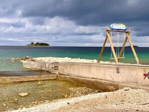 Ein Strand mit einer Schaukel und einer Betonkonstruktion.