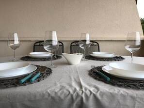 Ein Tisch für vier Personen, gedeckt mit weißen Tellern, klaren Weingläsern und türkisfarbenem Besteck.