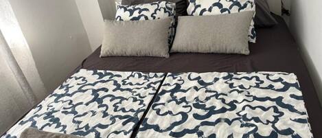 A bed with a patterned bedspread, two pillows, and a bedside lamp.