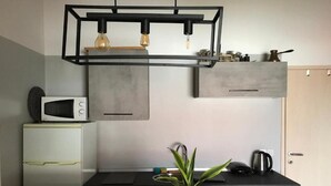 Une cuisine moderne avec un plan de travail noir, un micro-ondes blanc, une plante en pot et un luminaire suspendu.