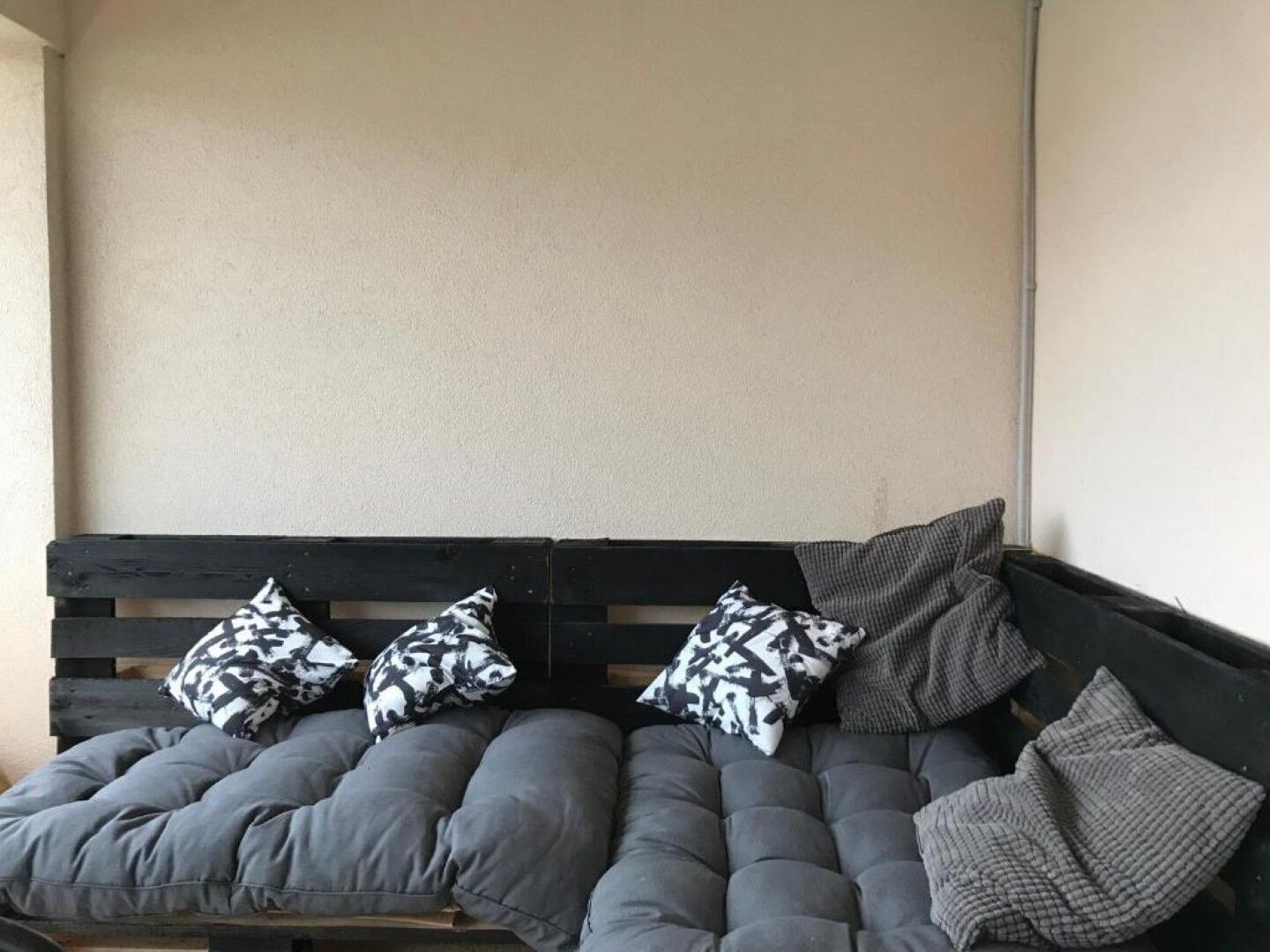 Un sofà gris amb tres coixins estampats i una manta de llana gris.