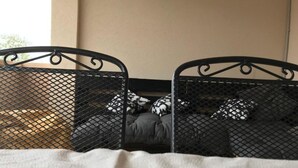 Un lit avec un cadre en métal et un drap blanc, agrémenté d’oreillers à motifs noirs et blancs.