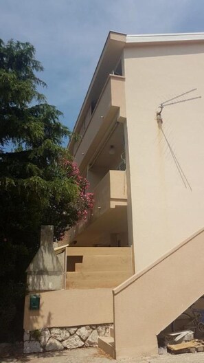 Ein beiges Gebäude mit einer Treppe, die zu einem Balkon führt.