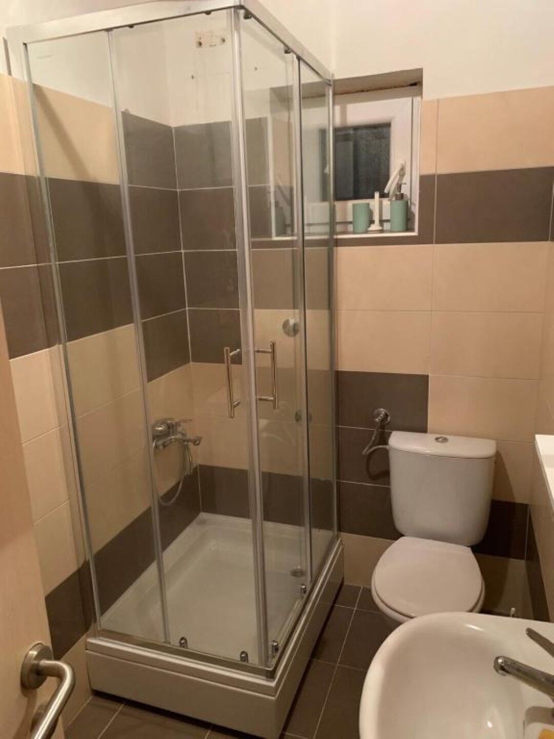 Une salle de bain avec une douche à parois de verre, des toilettes et un lavabo.