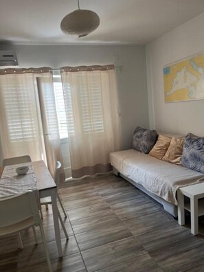 Ein gemütliches Zimmer mit Holzboden, einem Bett mit gemusterten Kissen, einem kleinen Tisch mit einer Schale und einer Karte an der Wand.