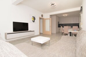 A modern living room with a flat-screen TV, a white coffee table, and a sofa. - Apartments Jozak (Trogir)