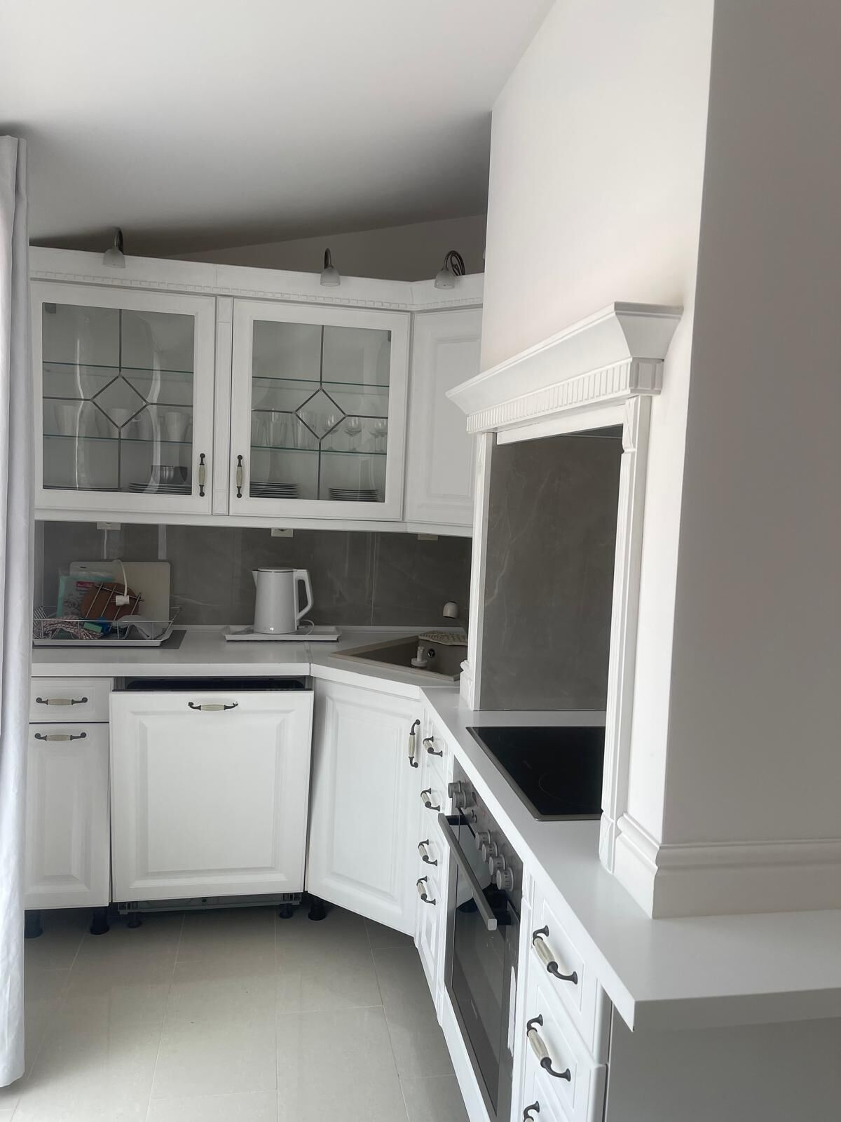 A kitchen with white cabinetry, a built-in oven, and a microwave.