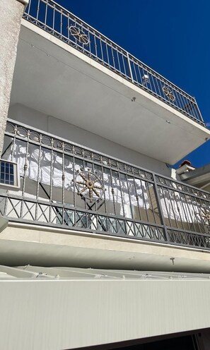 Ein Gebäude mit einem Balkon, der mit verzierten Metallgeländern und einem großen Fenster ausgestattet ist.