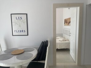 Ein Zimmer mit einem weißen Tisch, einem gerahmten Kunstwerk mit Text und einer Tür zu einem anderen Raum.