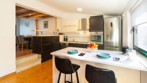 A modern kitchen with a central island, stainless steel appliances, and a dining area visible in the background. - Apartments Seafront Paradise (Stomorska)