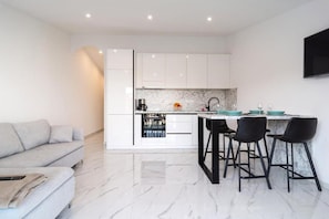 A modern kitchen with white cabinets, a marble countertop, and black bar stools. - Apartments Seafront Paradise (Stomorska)
