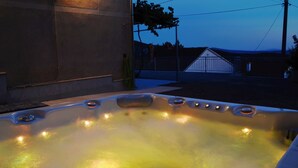 A hot tub with multiple jets, a concrete wall, and a metal fence in the background. - House Martin (Vinodol)