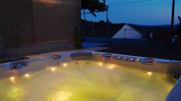 A hot tub with multiple jets, a concrete wall, and a metal fence in the background.