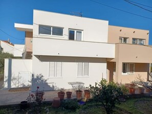 A modern two-story residential building with a flat roof, white exterior walls, and multiple windows. - Apartments Ornela (Split)